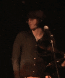 a man in a black shirt is giving the middle finger in front of a microphone