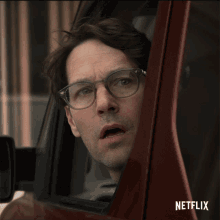 a man wearing glasses looks out of a car window with netflix written on the bottom