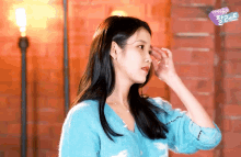 a woman in a blue sweater is standing in front of a red wall
