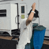 a person wearing a mask and a black hat is standing in front of a trailer
