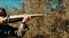a man is holding a rifle with the letter m on the barrel