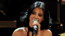 a close up of a woman singing into a microphone with rbd.gif in the corner