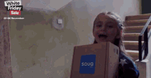 a girl holding a box that says souq.com on it