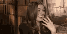 a woman with long hair is sitting at a table talking on a cell phone .