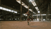 a man in a red and black costume is running in a large warehouse