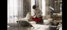 a man is putting a woman on a couch in a messy room .
