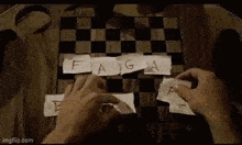 a person is playing a game of chess with pieces of paper on a wooden board .