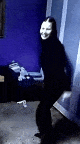 a woman with a mask on her face is dancing in a dark room