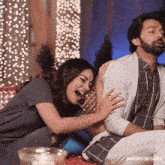 a man and a woman are sitting on a couch laughing .