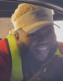 a man wearing a visor and a yellow vest sticks his tongue out