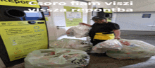 a man is holding a bag of garbage in front of a machine that says ' csoro fiam visz ' on it