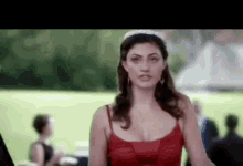 a woman in a red dress and tiara is standing in front of a field .