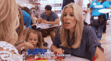 a woman sitting at a table talking to another woman with the words shut the fuck up above her