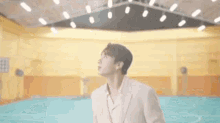 a man in a suit is standing in a basketball court looking up at the sky .