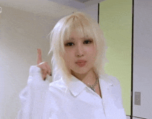 a woman with blonde hair and black nails is wearing a white shirt and a necklace .