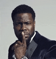 a man in a suit has his finger to his mouth