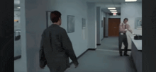 two men are walking down a hallway in a building