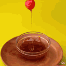 a person holds a cherry on a stick over a bowl of liquid