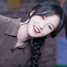 a woman with braided hair and red lipstick smiles