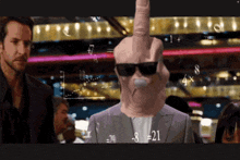 a man wearing sunglasses and a pink mask has a middle finger up in front of a screen with numbers on it