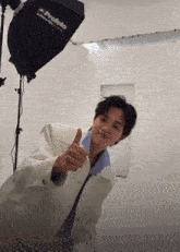 a young man giving a thumbs up in front of a profoto light