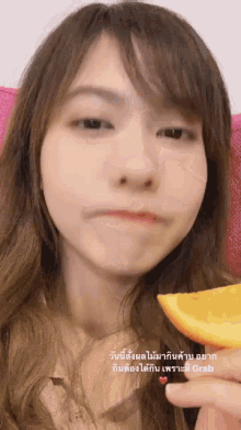 a woman is holding a slice of orange in front of her mouth