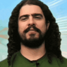 a man with long curly hair and a beard wearing a green shirt
