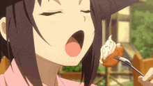 a girl in a pink shirt is eating a piece of food on a fork