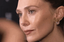 a close up of a woman 's face with a pair of earrings on .