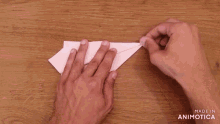 a person is making a paper airplane with the words made in animotica written on the bottom