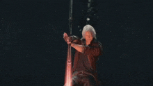 a man in a red coat is holding a sword that is surrounded by fire
