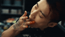 a close up of a person eating something with a tattoo on their hand