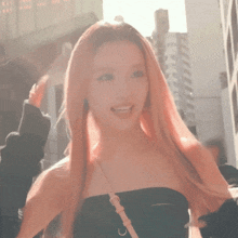 a woman with pink hair wearing a black off the shoulder top