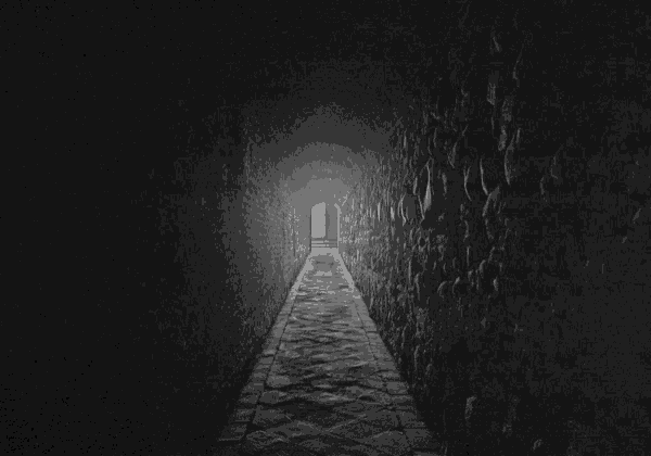 a black and white photo of a dark tunnel with a light at the end
