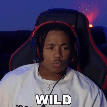 a man wearing headphones is sitting in a chair and saying wild