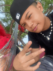 a young man wearing a black hat and a necklace with the letter b on it