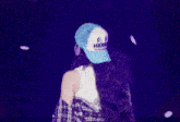 a woman wearing a plaid shirt and a blue hat is singing into a microphone and making a heart shape with her hands