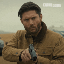 a man in a brown jacket holds a gun in front of a countdown logo
