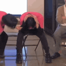 a man in a pink shirt is sitting on a chair with his head in his hands