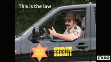 a man in a sheriff 's uniform is driving a black vehicle
