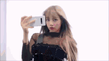 a woman is taking a selfie with her cell phone in front of a mirror .
