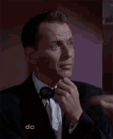 a man in a suit and bow tie is adjusting his tie