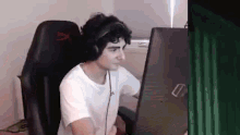 a man wearing headphones is sitting in a chair in front of a computer .