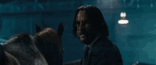 a man in a suit and tie stands next to a horse