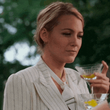a woman in a striped suit holds a martini glass