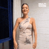 a woman in a dress is standing in front of a window and smiling .