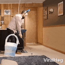 a man is playing a game of golf in a living room with the words viralhog on the bottom right