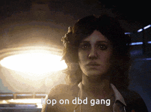 a woman says " hop on dbd gang " while looking at the camera