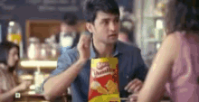 a man is holding a bag of chips while talking to a woman