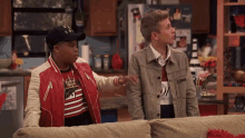 two boys are standing next to each other on a couch in a kitchen .